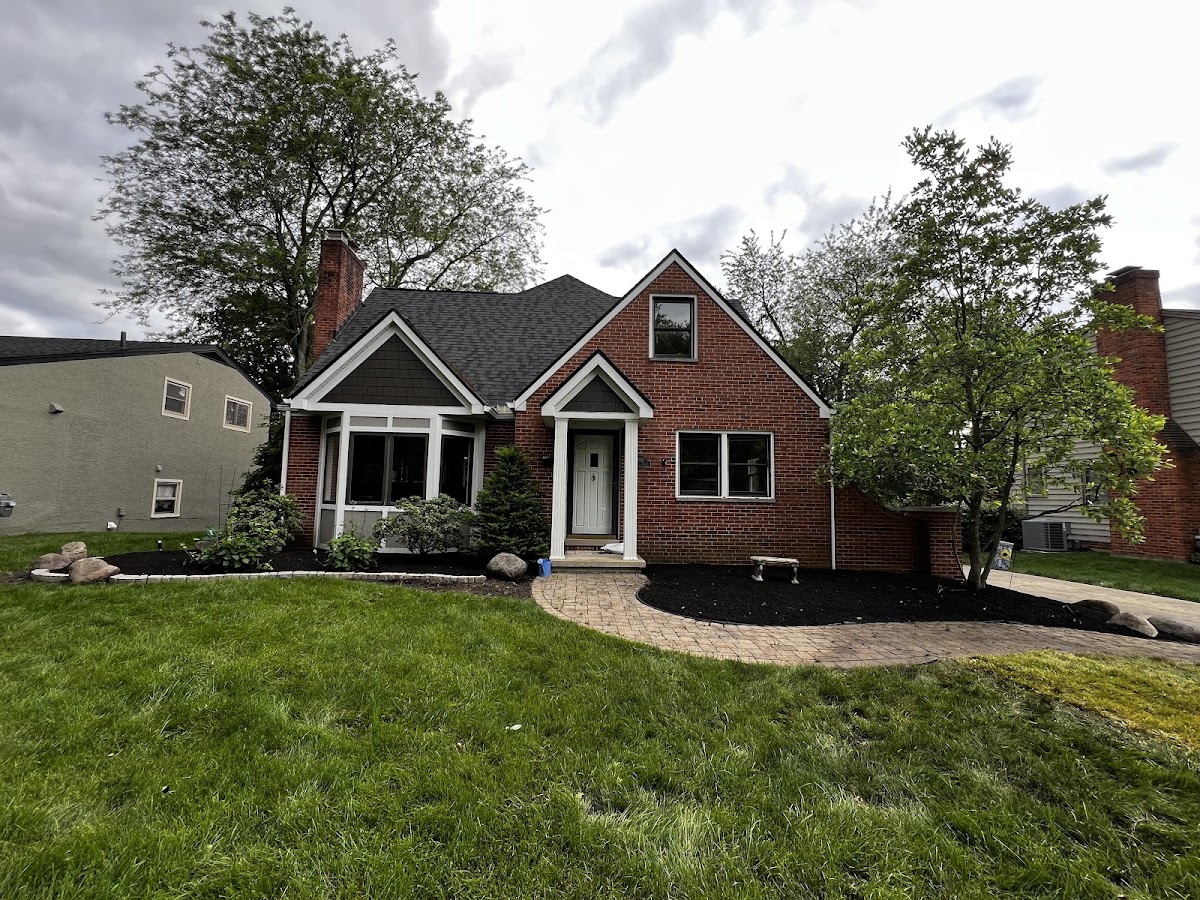 A finished paver walkway with mulch beds, boulders, and a fire pit
